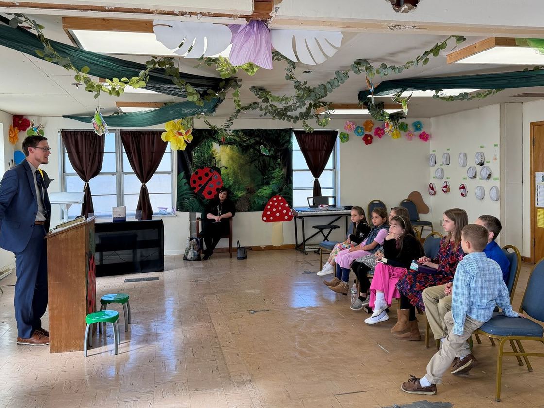 Children seated in the Junior Church room listening to a teacher at a small pulpit