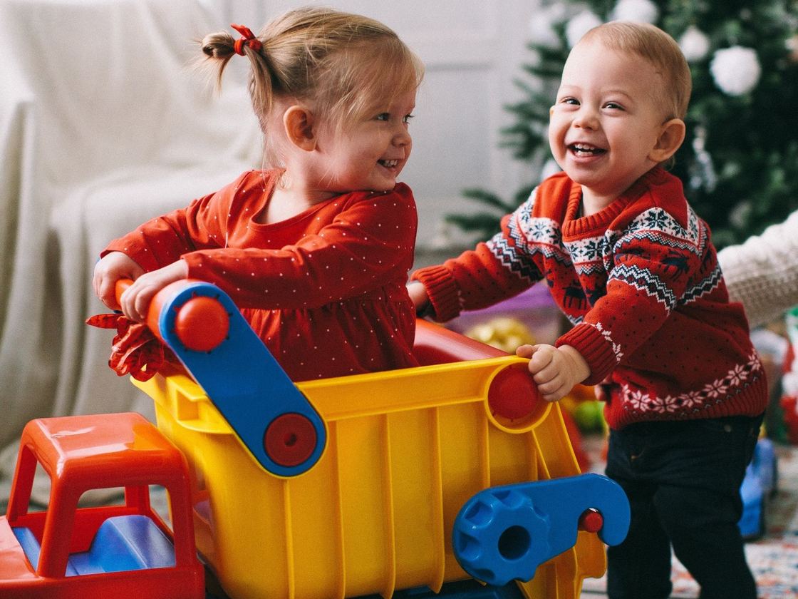 Two toddlers playing together in a toy truck