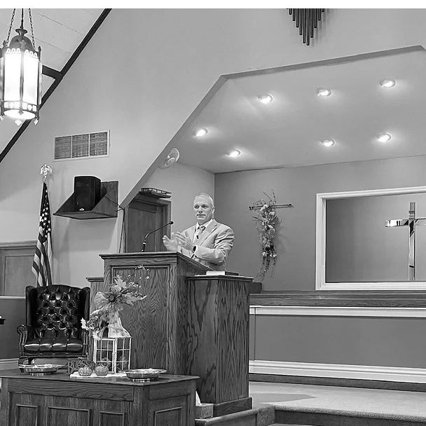 Pastor Mike Leonard preaching from the pulpit, in black and white