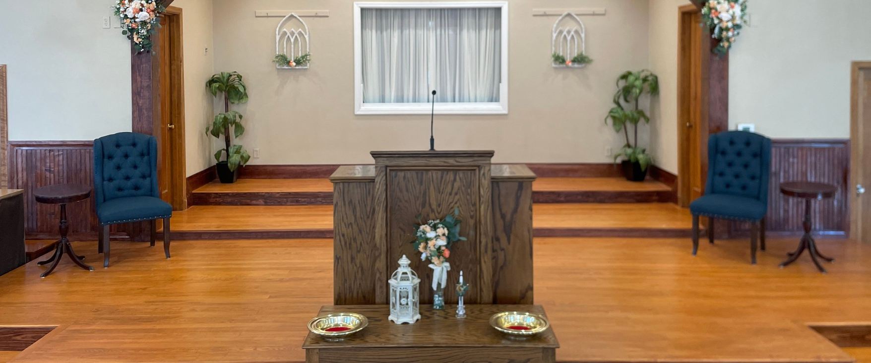 The sanctuary platform with the wooden pulpit, flowers, and two blue chairs