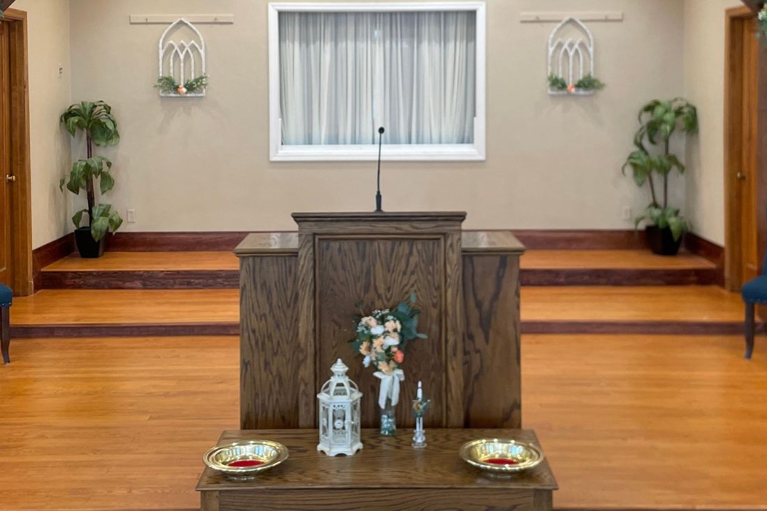 The sanctuary platform with the pulpit, flowers, and two blue chairs